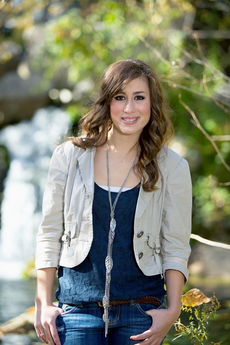 Smiling senior wearing a gray cardigan and layered necklaces