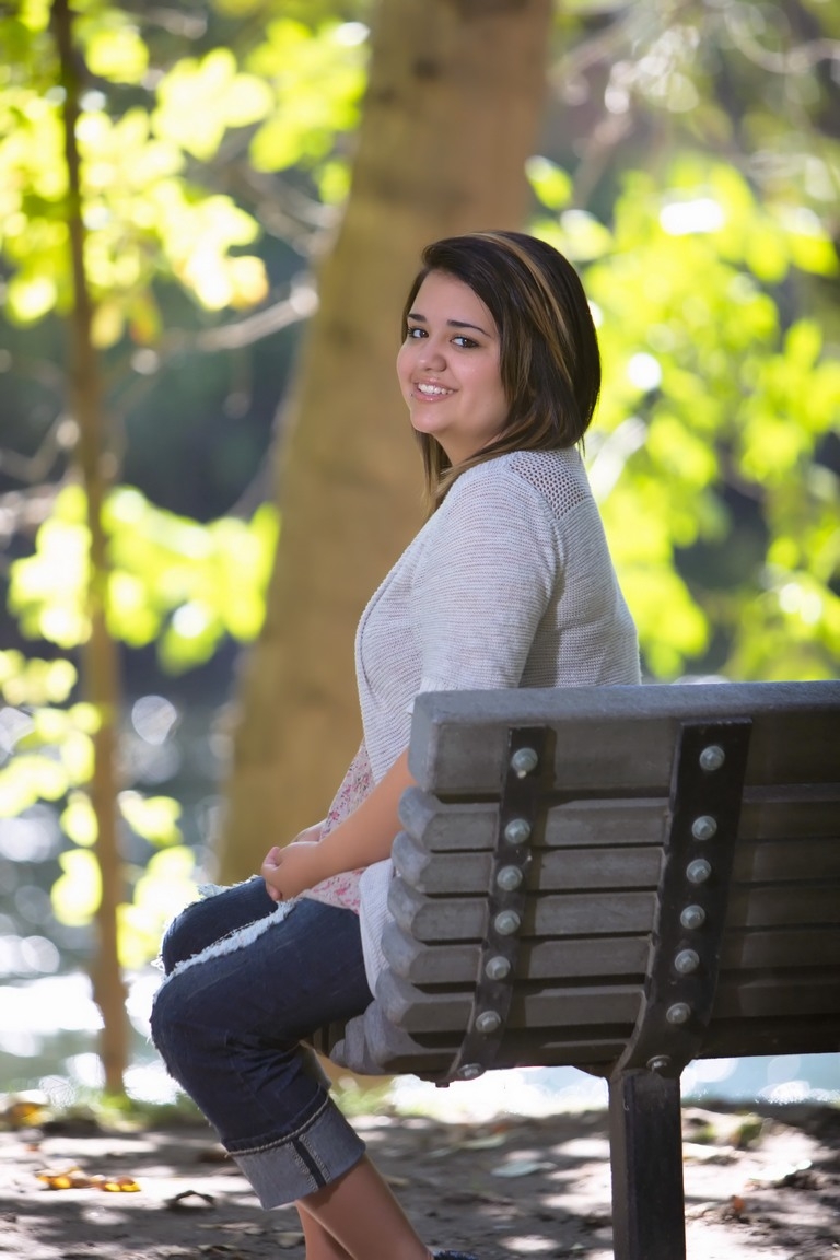 Senior in a white top seated on a park bench