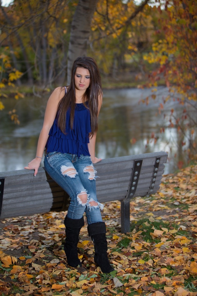 Senior in a blue top seated on a bench outdoors