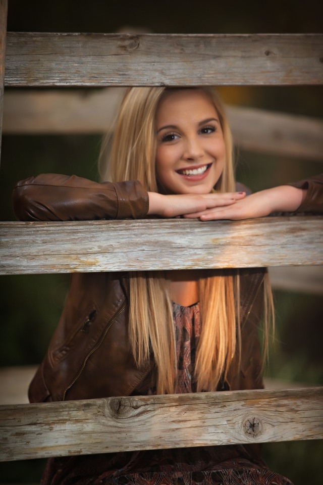 Smiling senior resting their chin on a wooden railing
