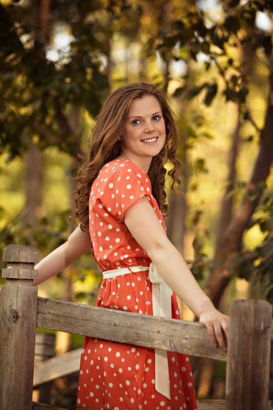Senior in an orange patterned top among trees
