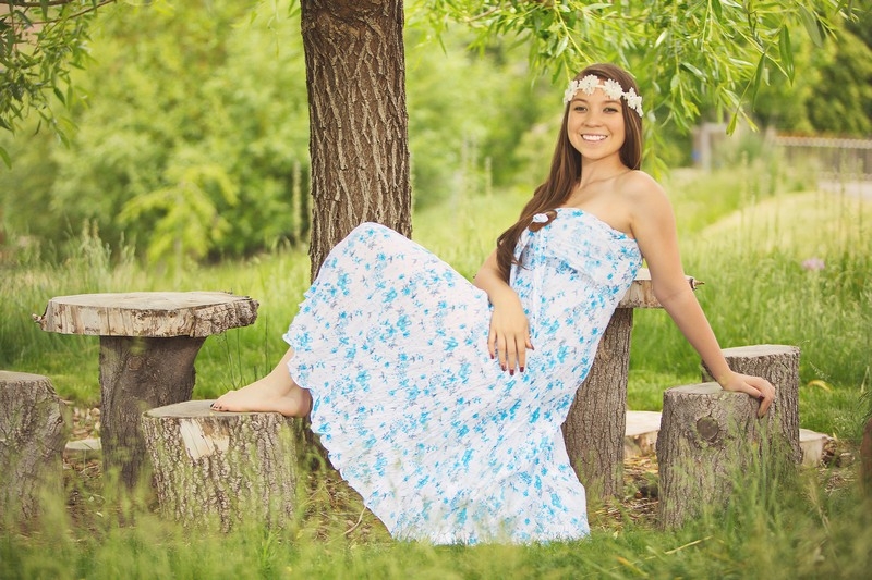 Senior in a floral dress seated on a bench in a field